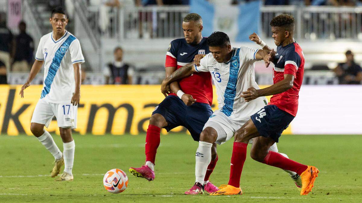 El jugador de Guatemala Alejandro Galindo (centro) trata de pasar la marca de los cubanos Neisser Sandó (der.) y Modesto Méndez, en el partido de la Copa Oro celebrado el 27 de junio de 2023 en el DRV PNK Stadium de Fort Lauderdale, Florida.