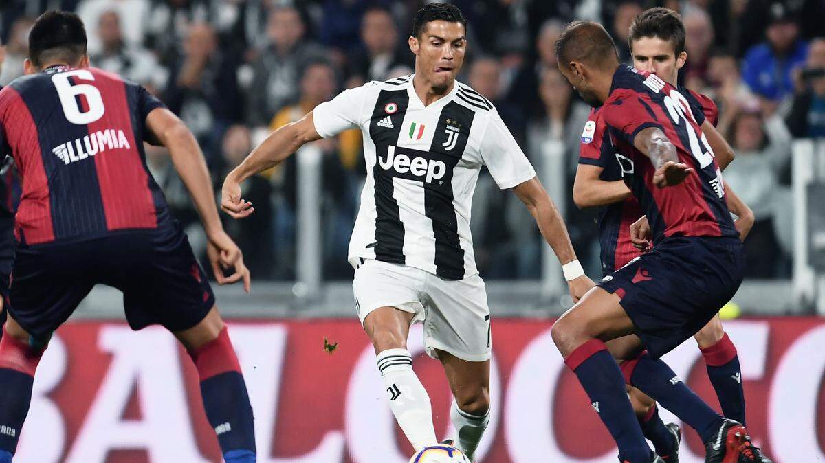 El delantero de Juventus Cristiano Ronaldo (centro) trata de pasar la defensa del Bolonia, en el partido celebrado el 26 de septiembre de 2018 en Turín, Italia.