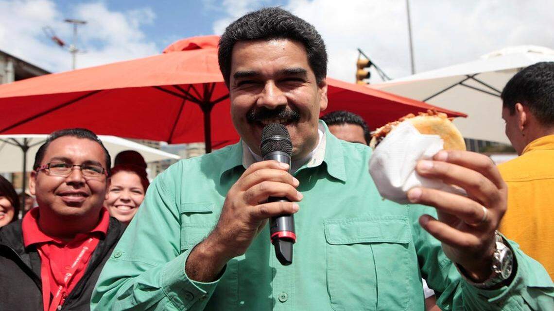 El presidente de Venezuela Nicolás Maduro degusta una tradicional arepa durante una visita a un mercado del centro de Caracas, el 24 de enero de 2015. 