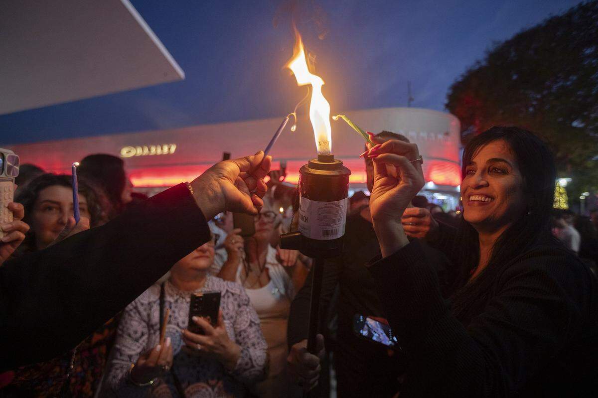 Sara Arami enciende una vela durante el gran encendido de la menorá que marca la primera noche de Janucá en Lincoln Road, Miami Beach, Florida, el 14 de diciembre de 2025. El gran encendido de la menorá y el festival de Janucá dieron inicio a la primera noche de Janucá.