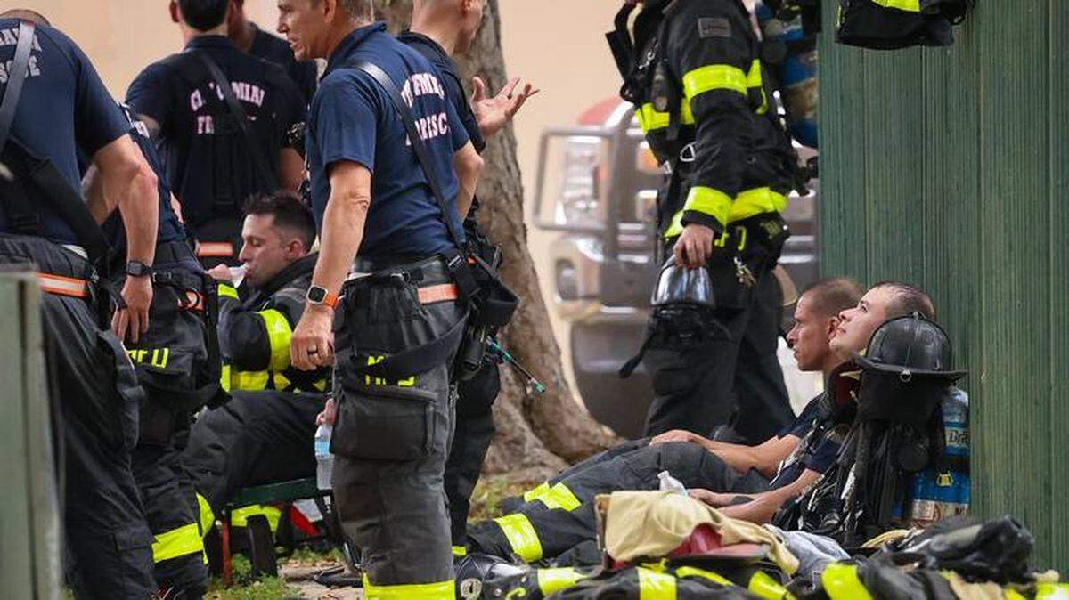 Bomberos de la Ciudad de Miami toman un breve descanso mientras otros se preparan para continuar luchando contra el incendio en Temple Court Apartments el 10 de junio de 2024, en Miami, Florida.