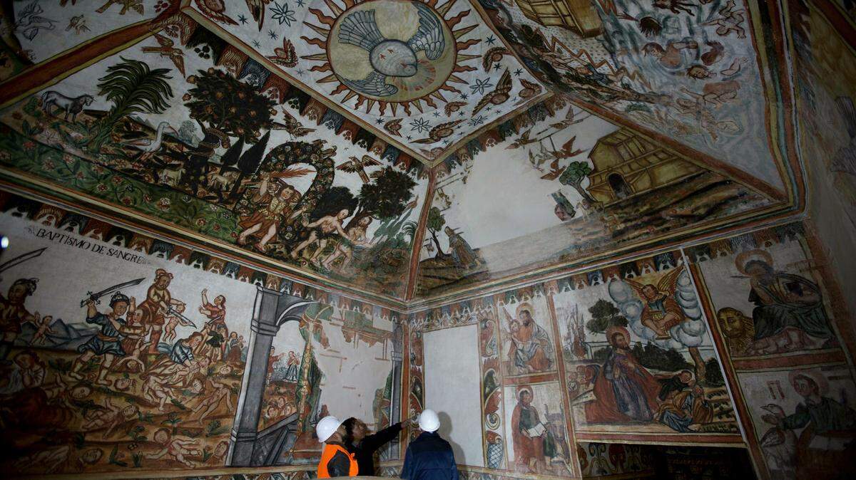El Padre Rafael Choque, al centro, habla con arquitectos expertos en restauración para arreglar los murales de la iglesia Curahuara de Carangas, en Bolivia. El espacio en blanco es parte del techo que colapsó en 1901.