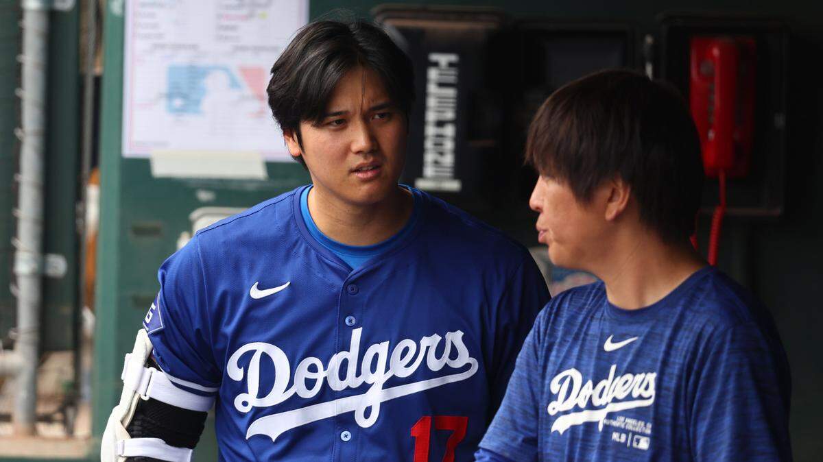 Shohei Ohtani (izq.) habla con su traductor Ippei Mizuhara en el dugout de los Dodgers en la pretemporada, el 12 de marzo de 2024 en Phoenix, Arizona.