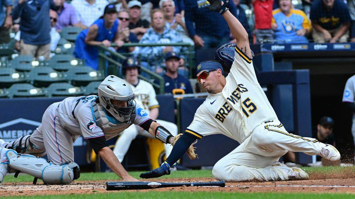 El jardinero de los Cerveceros Tyrone Taylor anota una carrera ante el receptor de los Marlins de Miami Jacob Stallings, en el quinto inning del partido celebrado el 14 de septiembre de 2023 en Milwaukee.