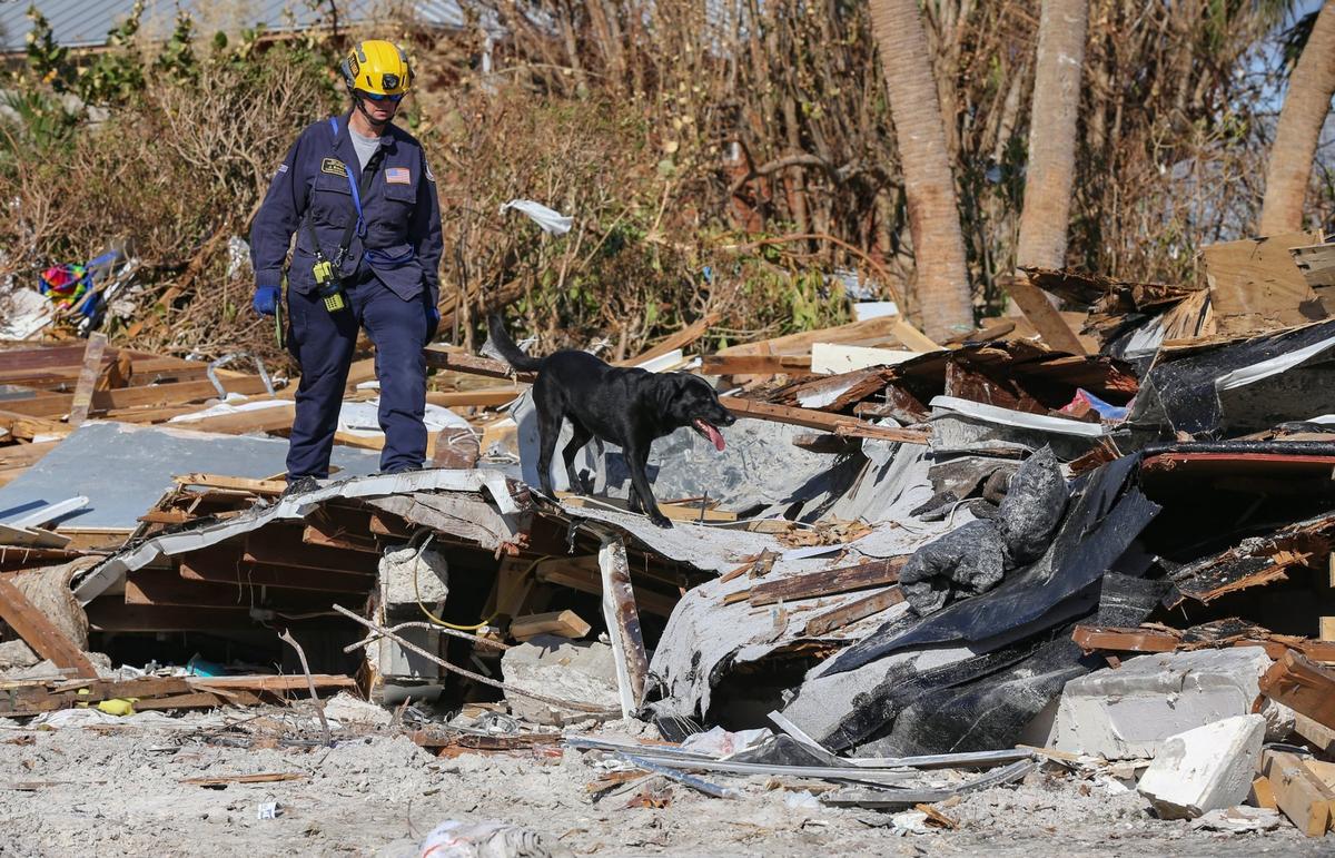 Un miembro del equipo de Búsqueda y Rescate Urbano Florida Task Force 2, J. Brown, inspecciona una casa con un perro de búsqueda y recuperación en Fort Myers Beach el lunes 3 de octubre de 2022.