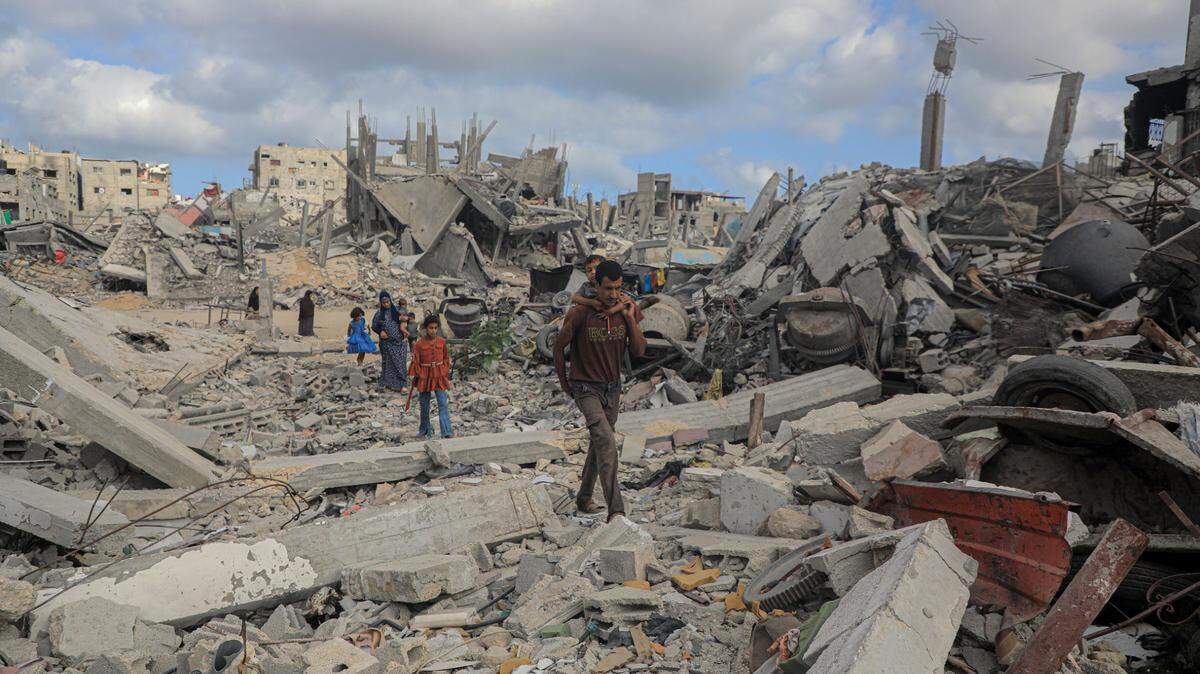Un hombre y su familia caminan sobre los escombros en la ciudad de Bani Suhaila, en el sur de Gaza, el 17 de junio de 2024.
