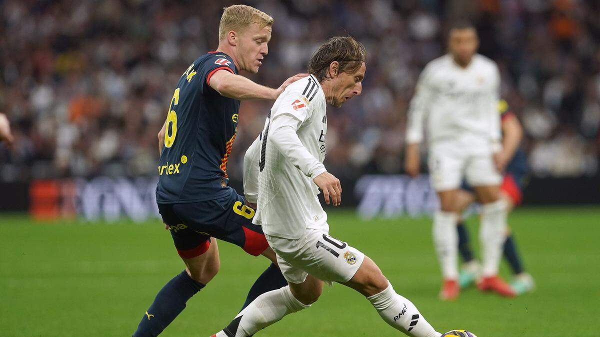 El astro del Real Madrid Luka Modric (der.) lucha por la pelota con Donny van de Beek, del Girona, en el partido de la liga española celebrado el 23 de febrero de 2025 en el estadio Santiago Bernabéu.