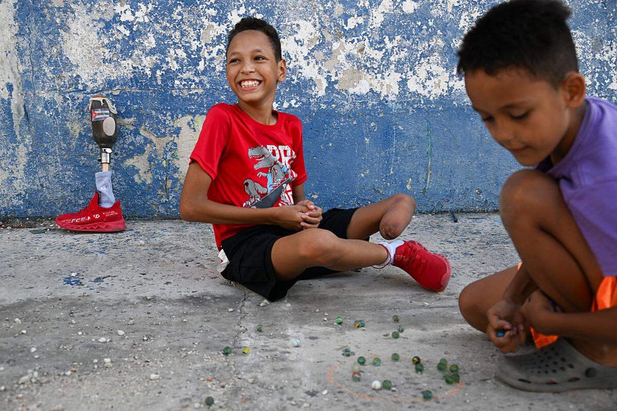 Juan José Guilarte juega a las canicas con un amigo en La Habana, el 25 de abril de 2026. Juan José, quien sueña con convertirse en deportista, nació en Cuba con una malformación congénita: su pierna izquierda se desarrolló únicamente hasta el fémur y la rótula.