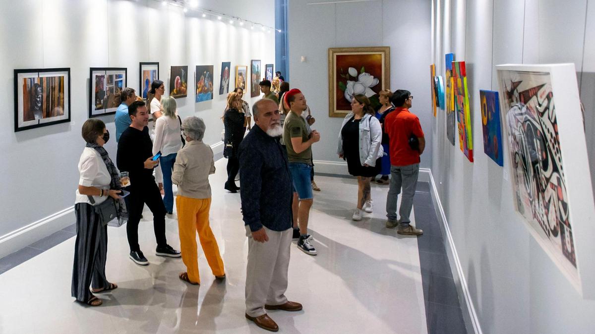 Las personas miran las decenas de obras de arte durante la exposición de artistas latinoamericanos en el Milander Center en Hialeah, Florida, viernes 30 de septiembre de 2022.