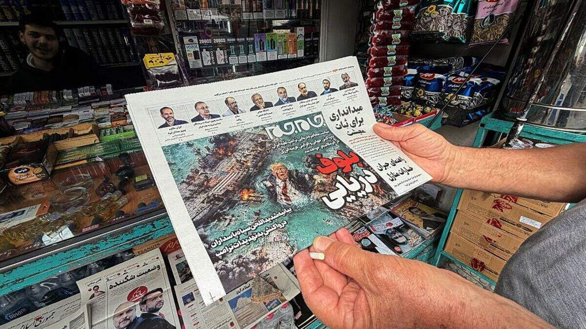 Un hombre observa la portada del periódico “Jam Jam”, a la venta en un quiosco, que presenta una caricatura del presidente estadounidense Donald Trump ahogándose en el estrecho de Ormuz bajo el titular “cuento marino”, en Teherán, el lunes, 13 de abril de 2026.