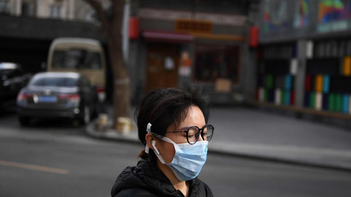 Una mujer usa una máscara facial como medida preventiva contra el coronavirus COVID-19 mientras camina por una calle en Beijing el 12 de marzo de 2020.