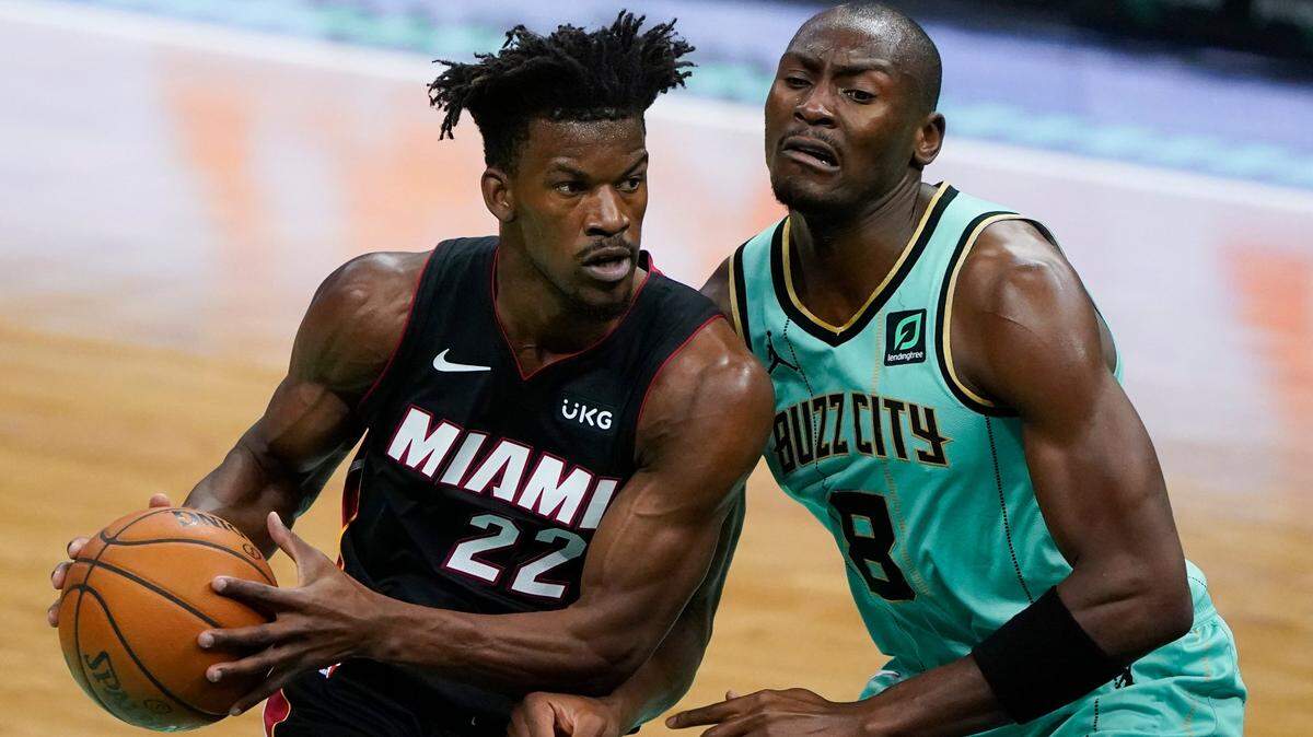 El delantero del Heat Jimmy Butler conduce hacia la canasta ante el centro de los Hornets, Bismack Biyombo, el viernes 26 de marzo de 2021 en Charlotte.