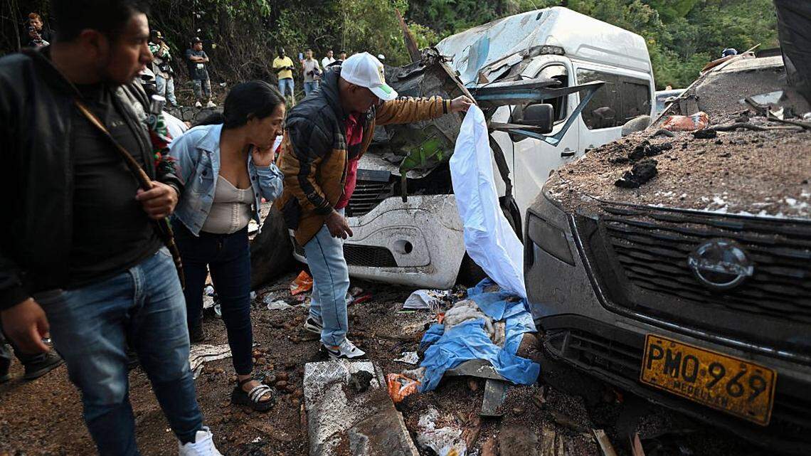 Contenido gráfico / Personas permanecen junto al cuerpo de una de las víctimas, cubierto con una sábana azul, tras un atentado con bomba en El Túnel, en la carretera Popayán-Cali, en Cajibío, departamento del Cauca, Colombia, el 25 de abril de 2026. Un atentado con bomba perpetrado el 25 de abril dejó siete personas muertas y 20 heridas en una zona de Colombia con fuerte presencia guerrillera, en medio de una oleada de ataques a poco más de un mes de las elecciones presidenciales, informó el gobernador de la región del Cauca.