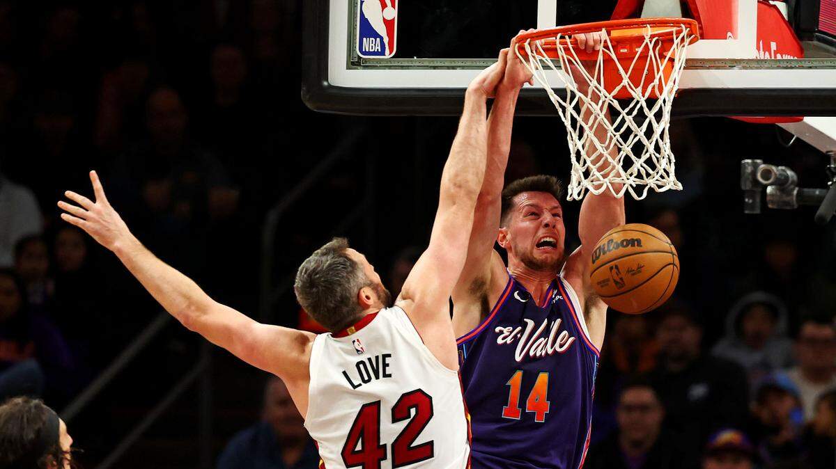 El jugador de los Suns Drew Eubanks (14) clava la pelota ante la marca de Kevin Love, del Heat de Miami, en el partido celebrado el 5 de enero de 2024 en Phoenix.