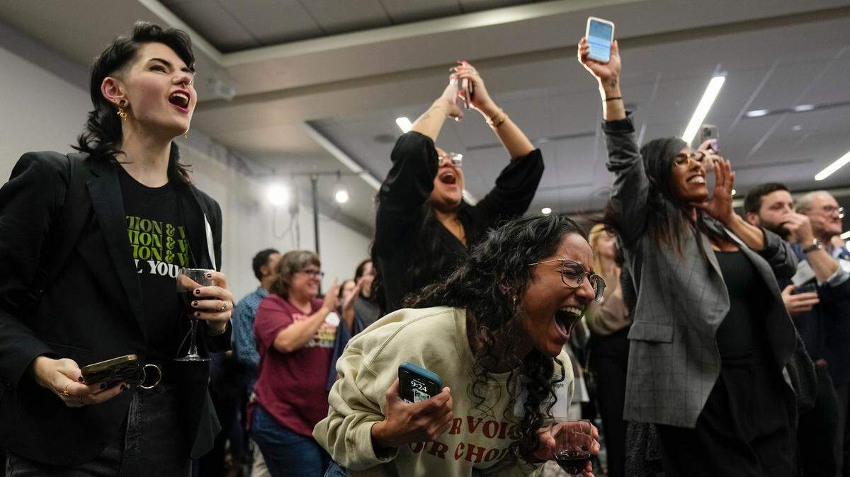 Mason Hickman (izq.) y Shakti Rambarran (der.) de la Alianza de Mujeres de Ohio (Ohio Women’s Alliance) celebran la victoria del Tema 1, que permite establecer el acceso al aborto como un derecho constitucional, el martes 7 de noviembre de 2023, en Columbus, Ohio.