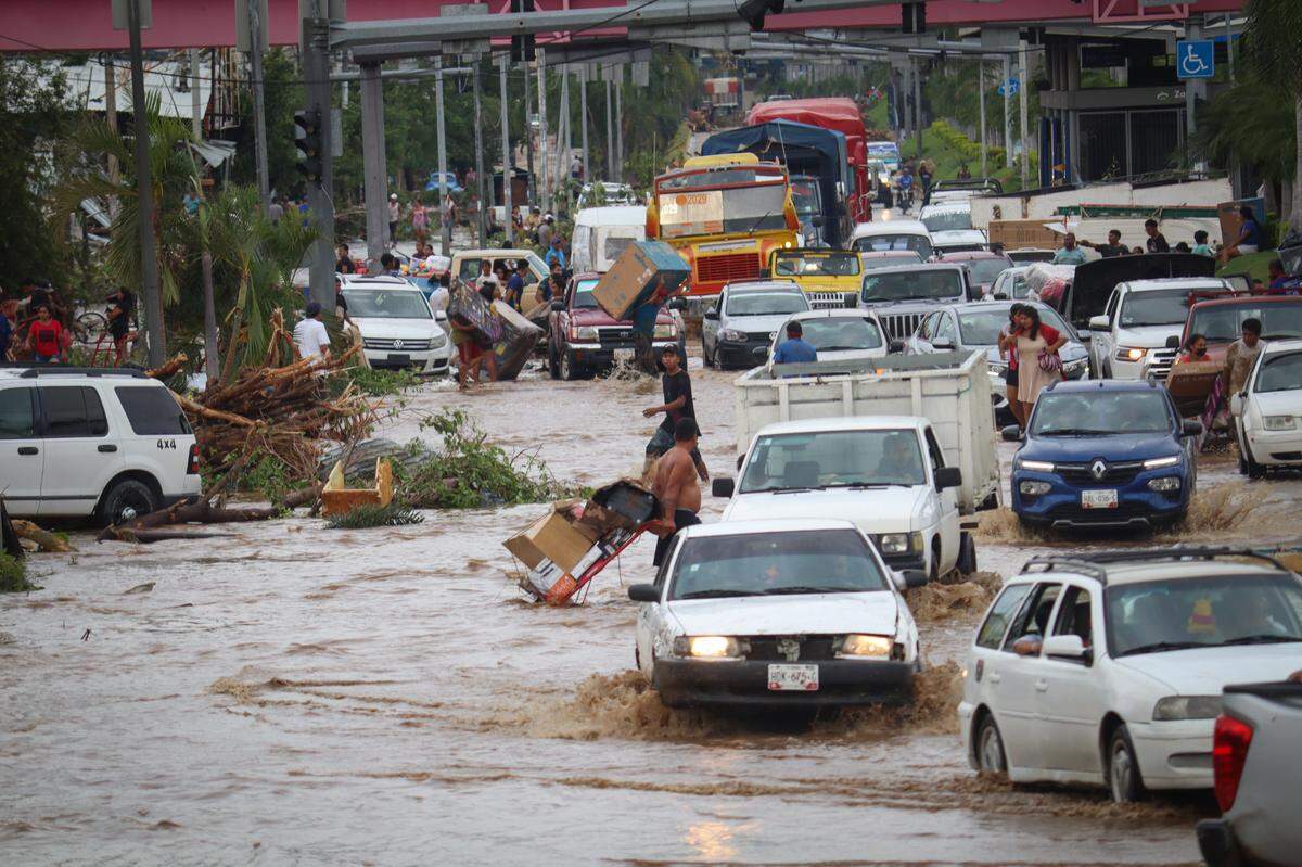 Decenas de autos tratan de desplazarse por una calle inundada por el impacto del huracán Otis, en Acapulco, México, el miércoles 25 de octubre de 2023.