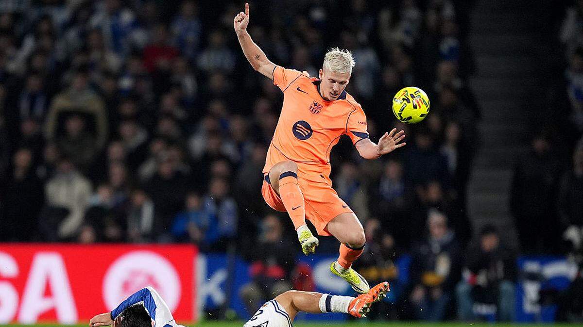 El jugador de Barcelona Dani Olmo (der.) trata de superar la marca de Jon Mikel Aramburu, de la Real Sociedad, en el partido de la liga española celebrado el 18 de enero de 2026 en el Estadio Anoeta en San Sebastián, España.
