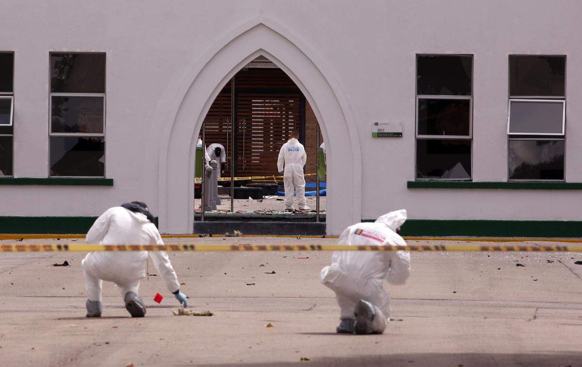 Peritos forenses inspeccionan el lugar donde un carro bomba causó una explosión este jueves en la Escuela General Santander de la Policía en Bogotá.