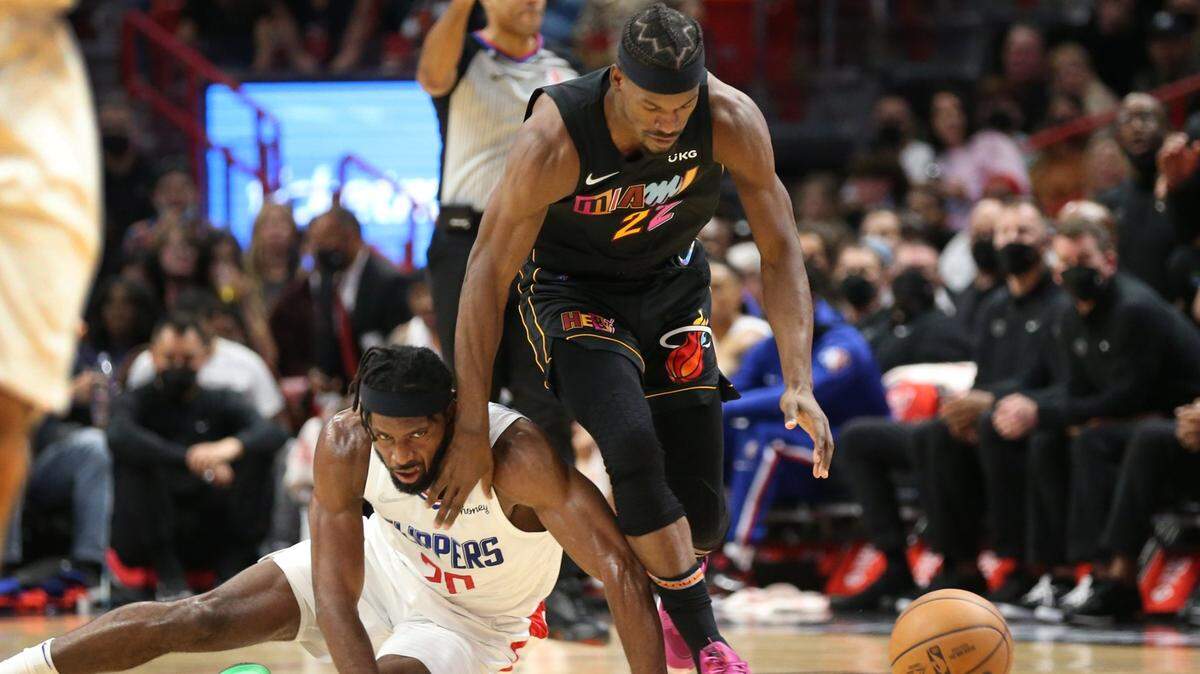 El delantero del Miami Heat Jimmy Butler (22) y el delantero de los LA Clippers Justise Winslow (20) persiguen un balón suelto en la primera mitad en el FTX Arena de Miami el viernes 28 de enero de 2022.
