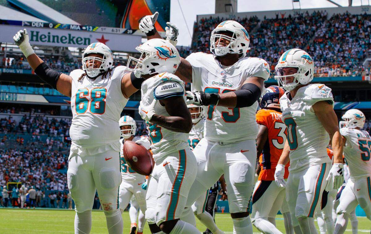 Los jugadores de los Dolphins celebran un touchdown anotado por el running back De’Von Achane (con el ovoide) ante los Broncos de Denver, el 24 de septiembre de 2023 en el Hard Rock Stadium en Miami Garden..