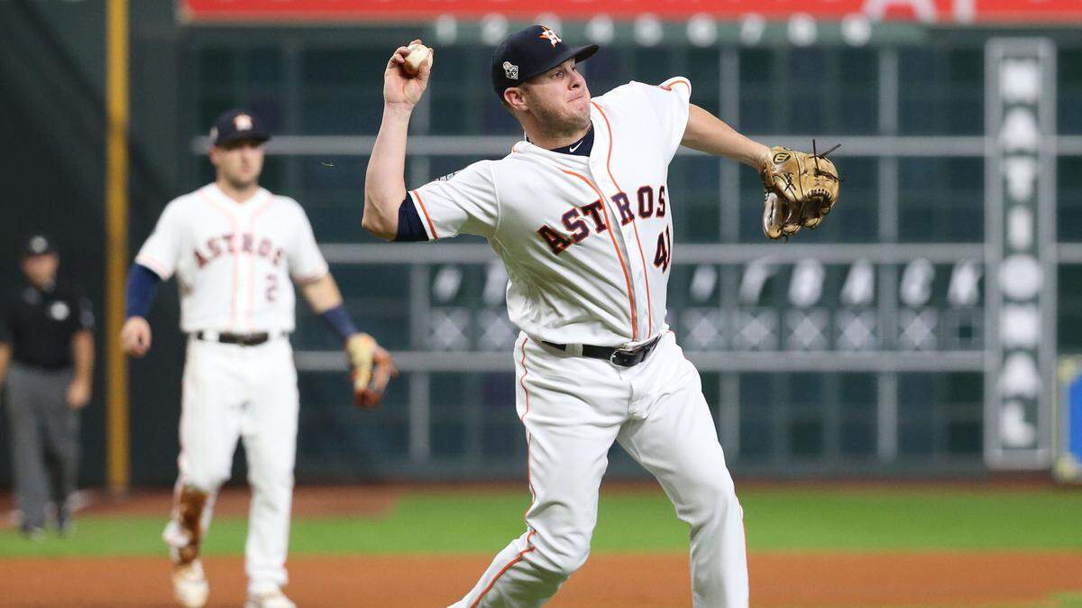 El relevista de los Astros de Houston Brad Peacock lanza a la primera base en la séptima entrada del sexto juego de la Serie Mundial el 29 de octubre de 2019, en una jugada donde el torpedero de los Nacionales de Washington, Trea Turner, fue declarado out por interferencia.