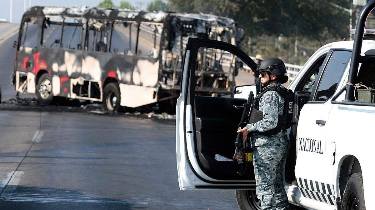 Un miembro de la Guardia Nacional se encuentra cerca de un autobús quemado por grupos del crimen organizado en respuesta a una operación en Jalisco para arrestar a un objetivo de seguridad de alta prioridad, en una de las principales avenidas de Zapopan, estado de Jalisco, México, el domingo 22 de febrero de 2026.
