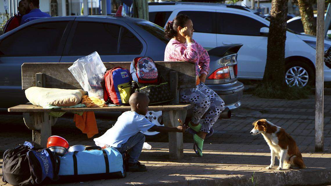 Un niño venezolano da de comer a un perro en una calle de Paracaima, el punto principal de entrada a Brasil de los venezolanos que huyen de la crisis en su país.