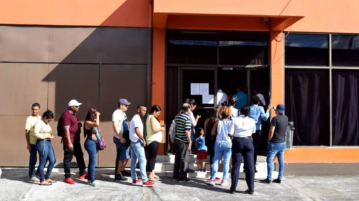 Numerosos inmigrantes, muchos de ellos venezolanos, esperan afuera de Living Water Community, una organización no gubernamental que atiende a solicitantes de asilo, en Puerto España. Trinidad.