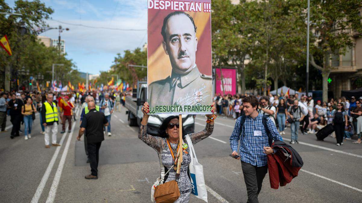 Manifestante porta pancarta con lema 'Los jóvenes despiertan. ¿(Francisco) Franco resucita?' durante la manifestación por el 12 de octubre de Movimiento Cívico d´Espanya i Catalans y Cataluña Suma por España, a 12 de octubre de 2025, en Barcelona, Cataluña (España). Esta movilización sale con el lema "Capital de la Hispanidad".