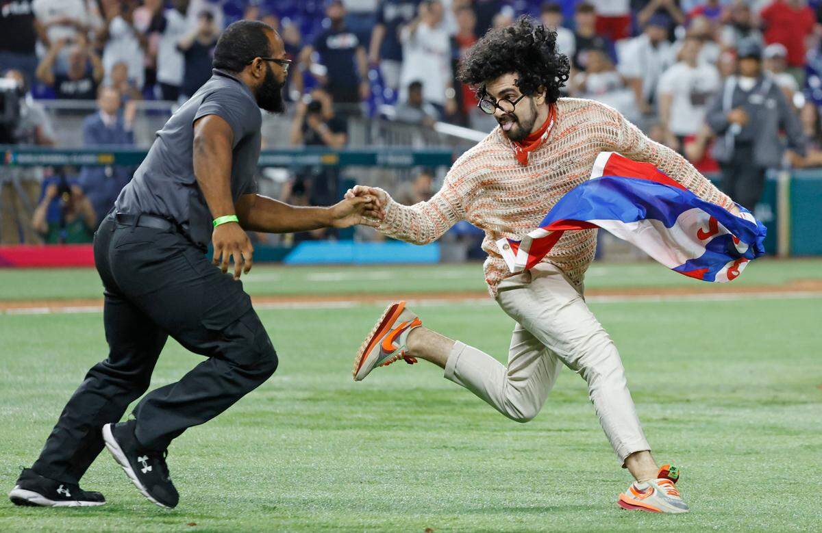 Un guardia de seguridad persigue a un manifestante que portaba una bandera cubana con las palabras “Patria y Vida” durante el partido entre Estados Unidos y Cuba en la semifinal del Clásico Mundial de Béisbol en el LoanDepot Park de Miami, el 19 de marzo de 2023.