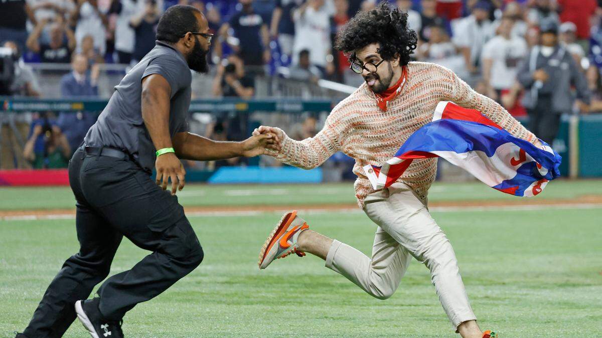 PATRIOTISMO EN el exilio. Un guardia de seguridad persigue a un manifestante que portaba una bandera cubana con las palabras “Patria y Vida” durante el partido entre Estados Unidos y Cuba en la semifinal del Clásico Mundial de Béisbol en el LoanDepot Park de Miami, el 19 de marzo de 2023.