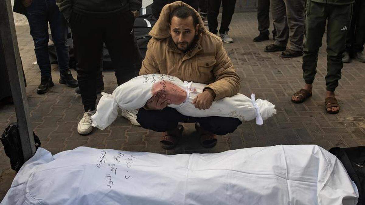 Un hombre sostiene el cuerpo envuelto de una niña mientras los palestinos lloran a sus muertos en el Hospital Al-Najjar tras un ataque aéreo israelí contra el campo de refugiados de Rafah, en el sur de la Franja de Gaza, el 21 de febrero de 2024. EFE/EPA/HAITHAM IMAD