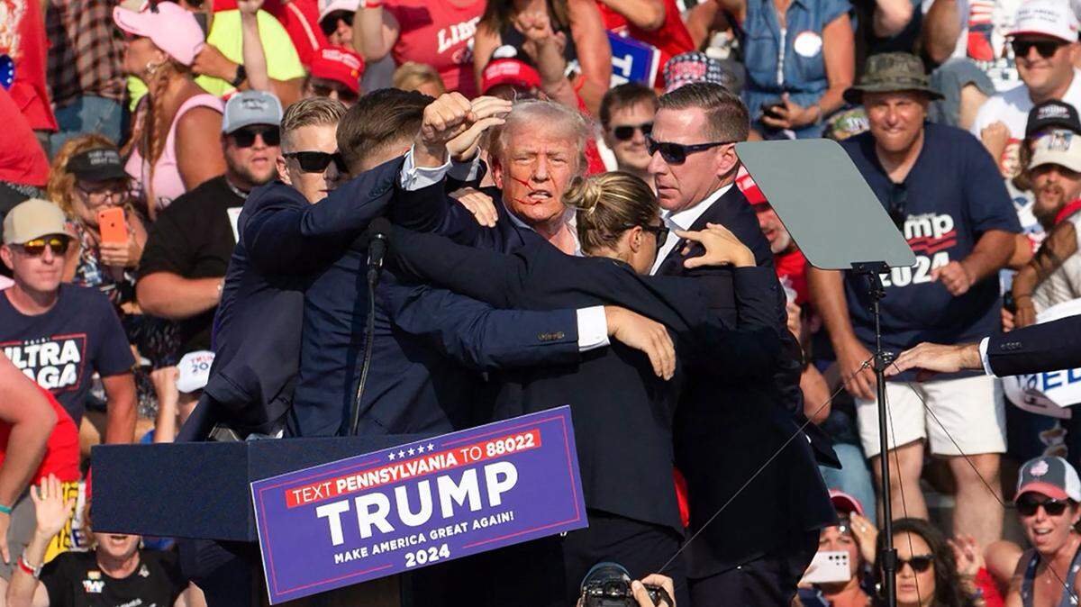 El expresidente Donald Trump aparece con sangre en su rostro mientras los agentes del Servicio Secreto intentan protegerlo y sacarlo de la tribuna en el condado Butler de Pennsylvania el sábado.