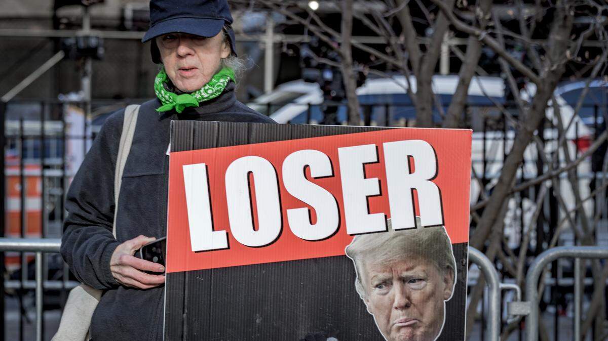Una mujer sostiene una pancarta con la palabra “Perdedor” (Loser) y la cara del expresidente Donald Trump, durante una protesta frente a un tribunal de Nueva York, el lunes 25 de marzo de 2024.