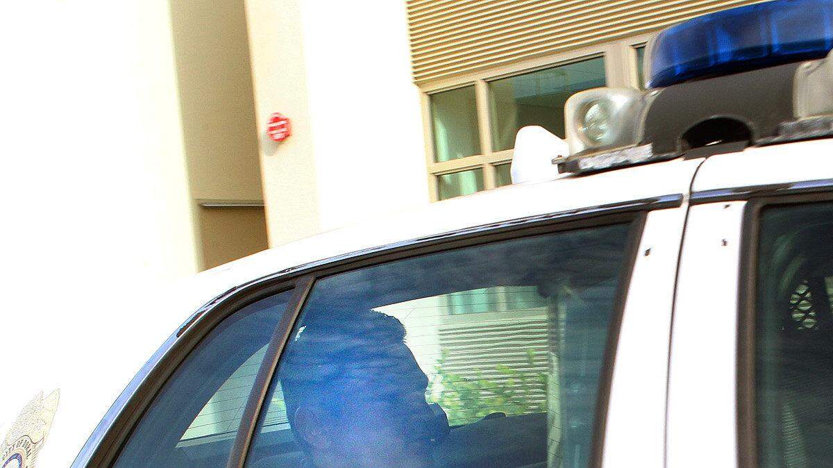 Venezuelan real estate developer Juan Carlos Tovar sits behind a City of Doral Police cruiser after being arrested for making false statements to the police on October 9,2013