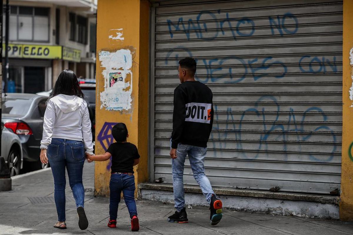 Personas caminan frente a un local comercial cerrado en Caracas, Venezuela.
