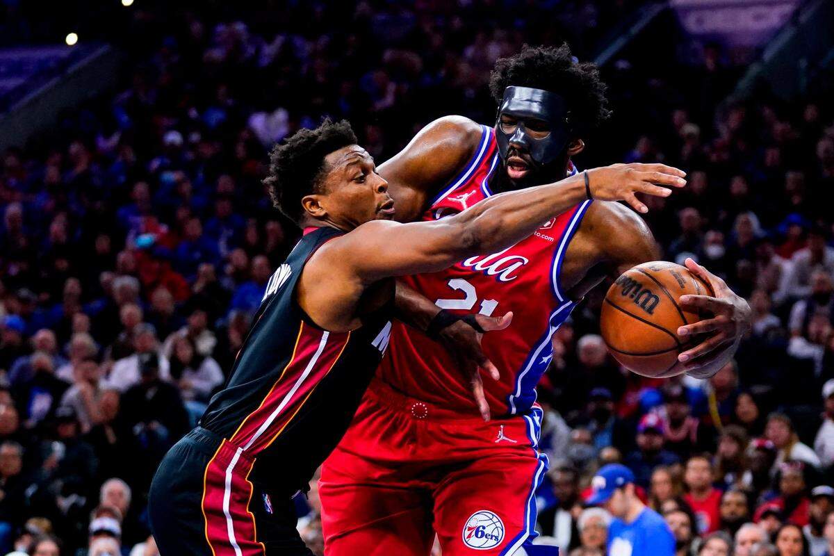 El armador del Heat Kyle Lowry (izq.) y el centro de los 76ers Joel Embiid luchan por la pelota en el cuarto partido de la serie de playoffs, celebrado el 8 de mayo de 2022 en Filadelfia.