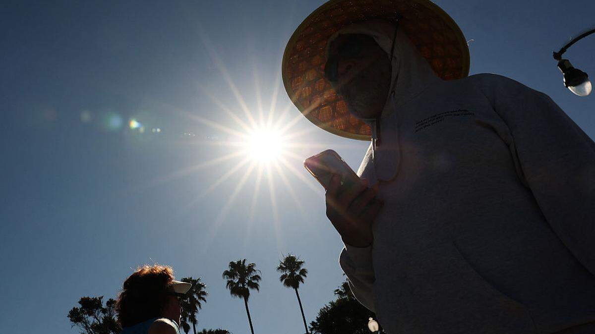 Una persona lleva puesto un sombrero para protegerse del sol matutino mientras camina por The Strand, en Redondo Beach (California), el 20 de marzo de 2026, durante una ola de calor. Según los expertos, la ola de calor —inusualmente temprana y de intensidad récord— que azotó el oeste de Estados Unidos el 20 de marzo es un fenómeno que ocurre una vez cada 500 años y es, casi con total certeza, consecuencia del cambio climático provocado por el ser humano.