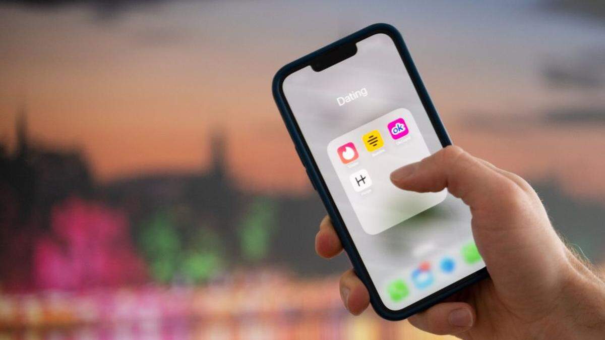Una mujer sostiene un teléfono con las apps de citas Tinder, Bumble, OkCupid y Hinge. 