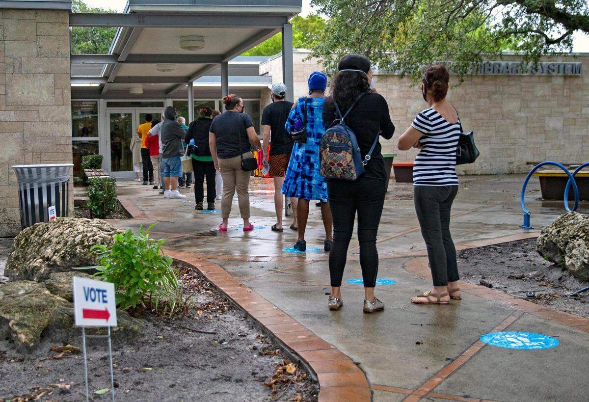 Las personas hacen fila para votar el primer día de votación anticipada para las elecciones generales en la biblioteca sucursal de Shenandoah, el 19 de octubre de 2020 en Miami, Florida.
