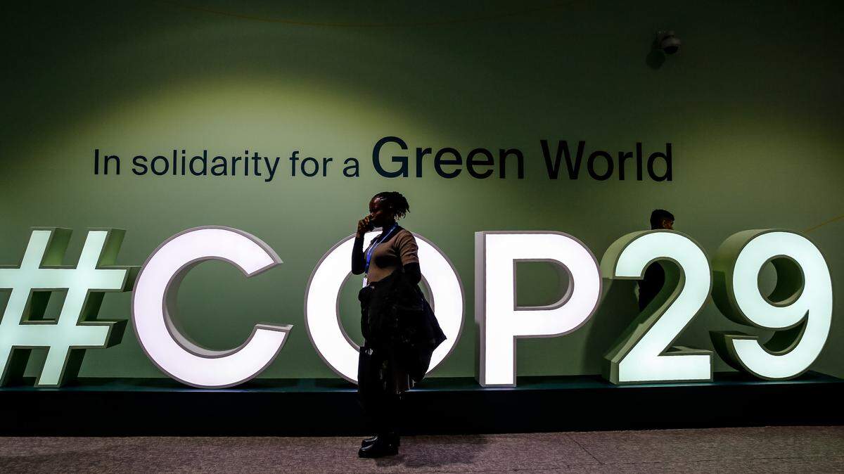 Los participantes pasan junto a un logotipo de la COP29, Conferencia de la ONU sobre el Cambio Climático, un evento organizado por la CMNUCC en el Estadio Olímpico de Bakú. La COP29, que se celebra del 11 al 22 de noviembre, se centra en el procedimiento de compensación de carbono y el Fondo de Pérdidas y Daños. 