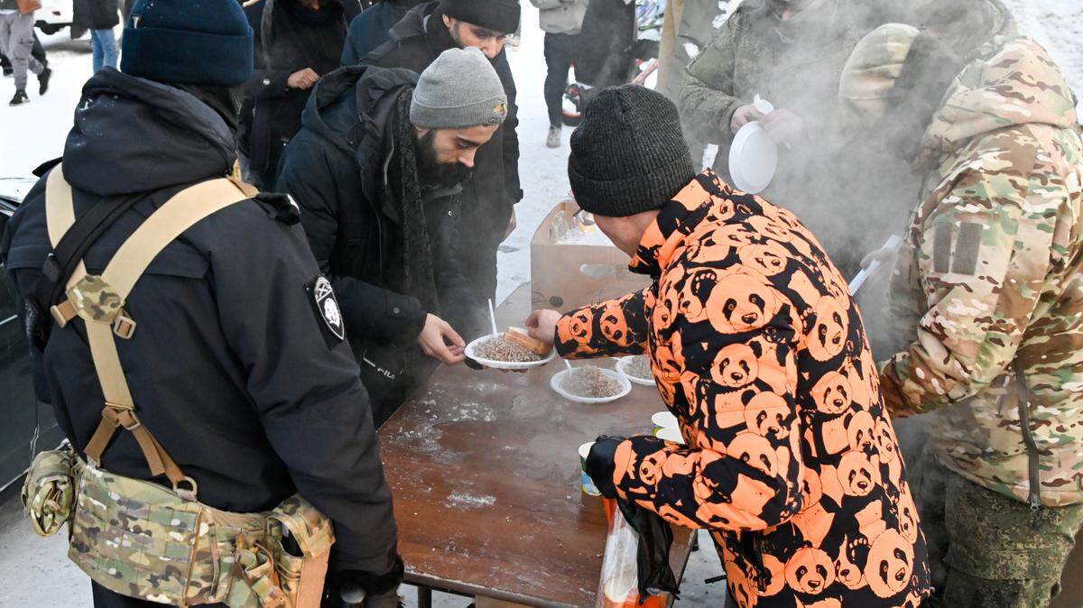 Inmigrantes reciben comida caliente en el punto de chequeo en Alakurttti, Rusia, antes de dirigirse al punto fronterizo de Salla-Kelloselka, entre Rusia y Finlandia, el 24 de noviembre de 2023.