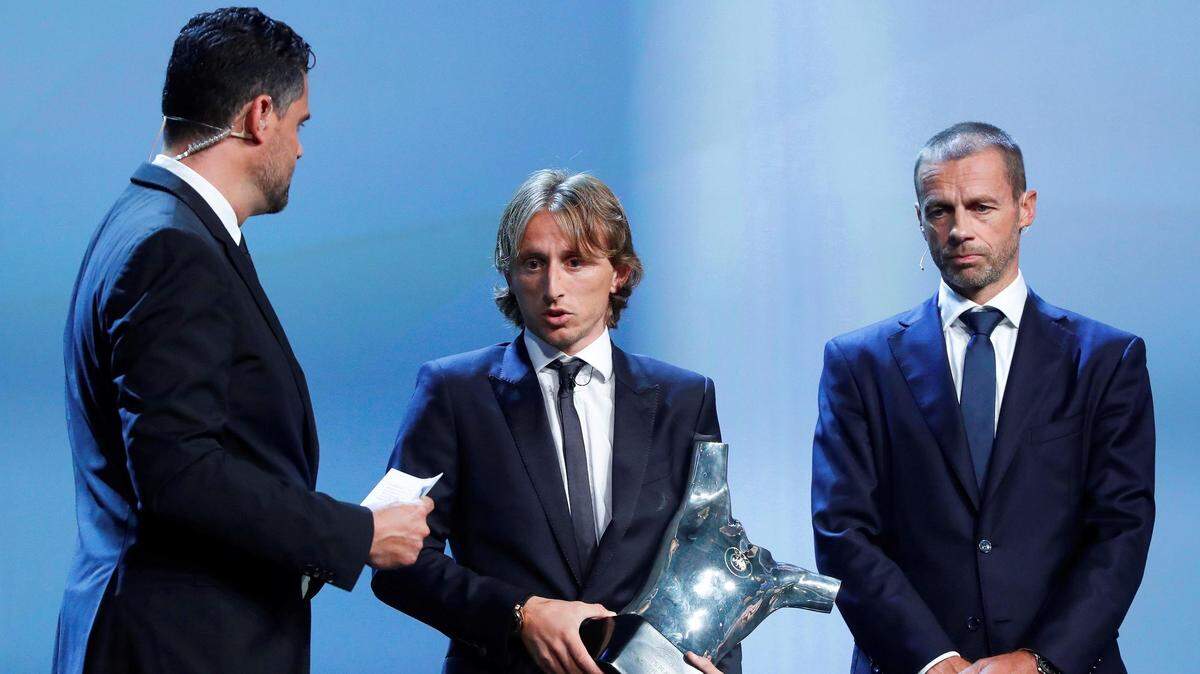 El futbolista croata del Real Madrid Luka Modric (centro) recibe el trofeo al mejor jugador de la última temporada de manos del presidente de la UEFA, Aleksander Ceferin (der.), durante la ceremonia de entrega de galardones de la UEFA en Mónaco el 30 de agosto de 2018.