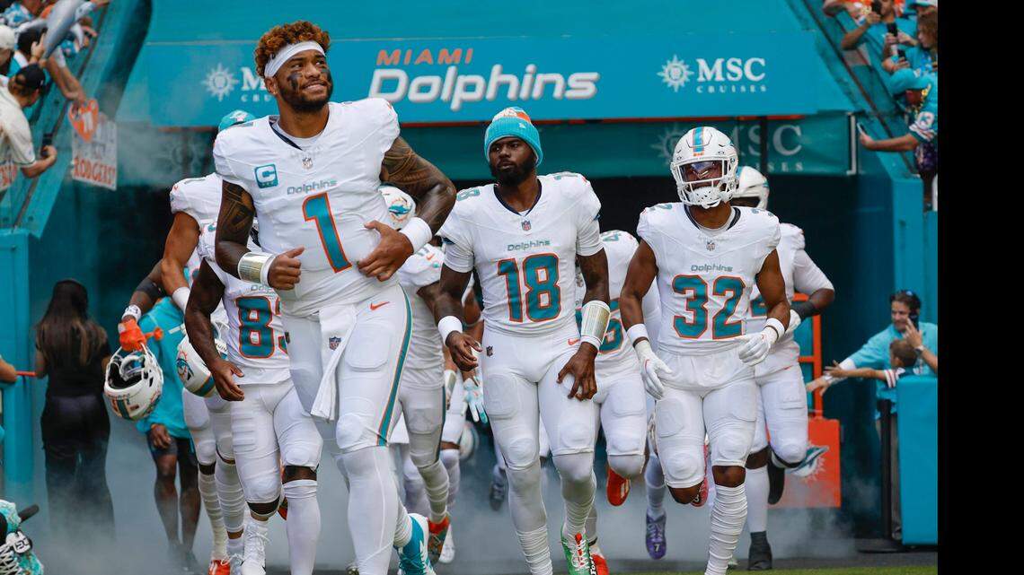 Miami Dolphins quarterbacks Tua Tagovailoa (1) and Tyler Huntley (18) run onto the field with teammates before the start of their NFL football game against the New York Jets at the Hard Rock Stadium in Miami Gardens, Florida on Sunday, December 8, 2024.