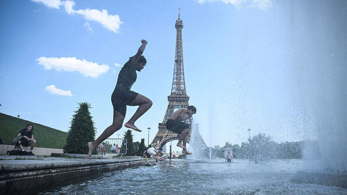 Personas se lanzan a la fuente del Trocadero, cerca de la Torre Eiffel, durante una ola de calor en París el 22 de junio de 2026. Esta reciente oleada de temperaturas excepcionalmente altas que afecta a Europa ha provocado la cancelación de eventos al aire libre, alteraciones en el transporte, el cierre de escuelas y la recomendación a los trabajadores de oficina de teletrabajar, mientras las autoridades emitían alertas sanitarias para proteger a las personas mayores y a los grupos vulnerables.