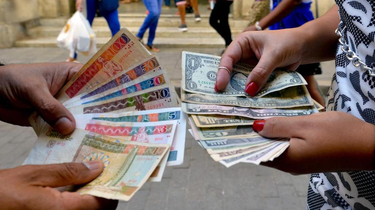 Cubanos muestran billetes de CUC y dólares en una calle en La Habana, el 10 de diciembre de 2019. 