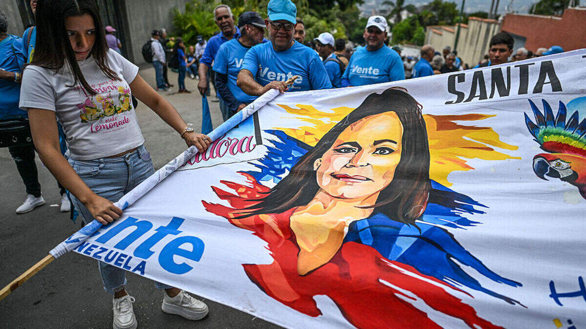 Partidarios de la líder de la oposición venezolana y Premio Nobel de la Paz, María Corina Machado, sostienen una pancarta alusiva a la dirigente mientras se congregan frente a la sede del partido político VENTE Venezuela —que abrió sus puertas por primera vez en 20 meses—, en Caracas, el 28 de marzo de 2026.