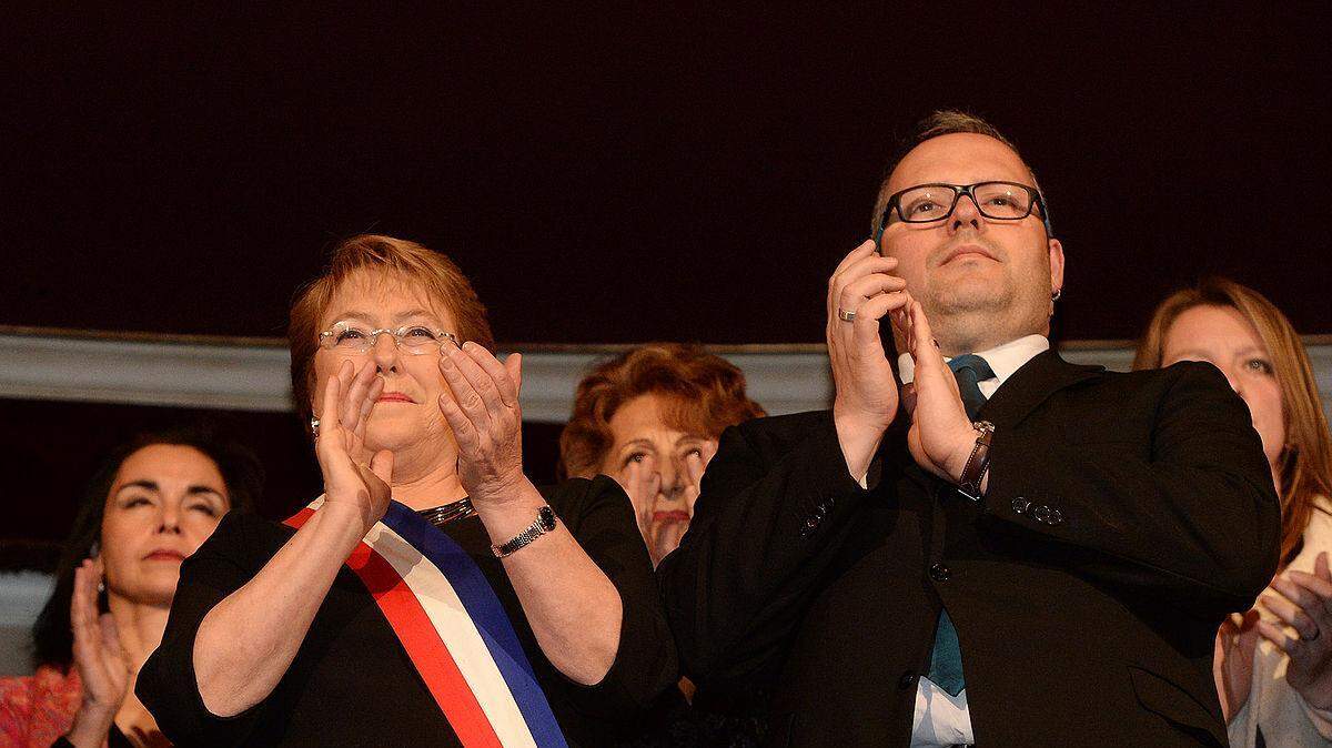 La presidenta de Chile Michelle Bachelet y su hijo Sebastián Dávalos asisten a la función de Gala con motivo de la celebración del 204º aniversario nacional, oportunidad en la que se presentará un Concierto sinfónico-coral. Disponible bajo la licencia CC BY 2.0 vía Wikimedia Commons.  
