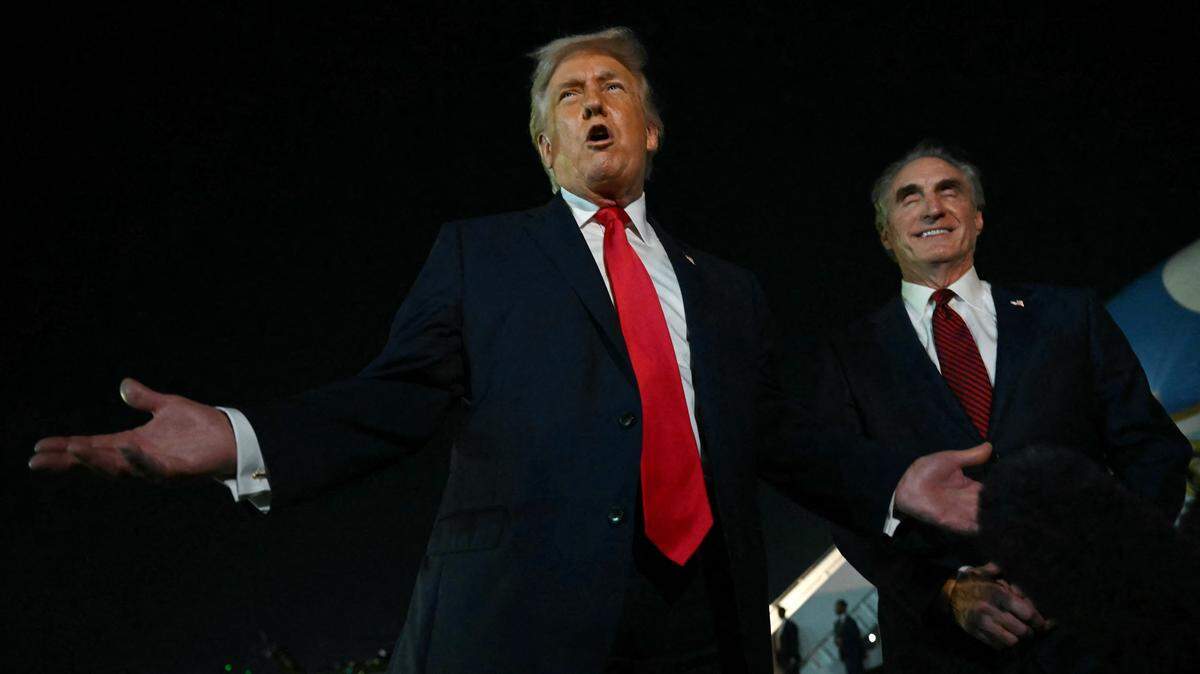 El presidente de Estados Unidos, Donald Trump, habla con periodistas mientras el secretario del Interior, Doug Burgum (R), reacciona, antes de abordar el Air Force One en el Aeropuerto Internacional de Palm Beach, en West Palm Beach, Florida, el 19 de enero de 2026.