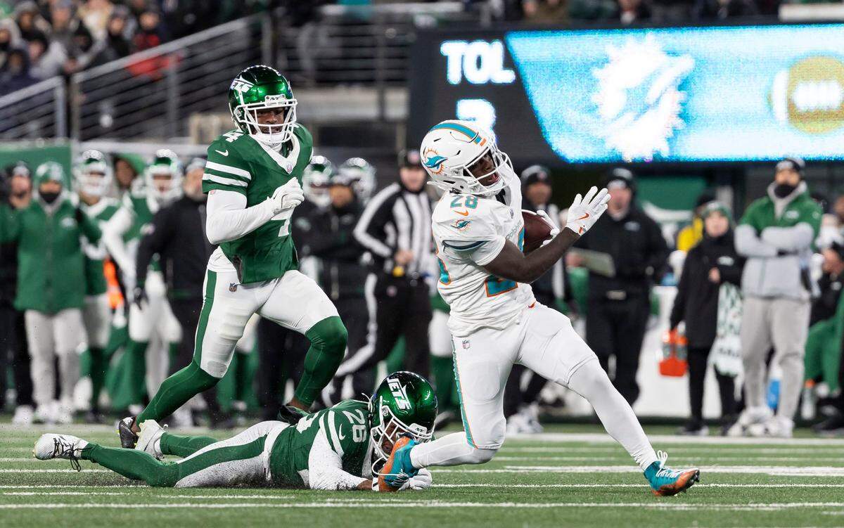 El running back de los Dolphins de Miami De’Von Achane (28) corre con el ovoide en el partido contra los Jets, celebrado el 5 de enero de 2025 en el MetLife Stadium en East Rutherford, Nueva Jersey.